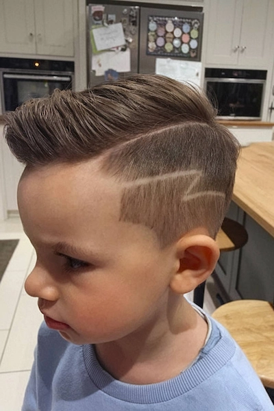 Dječja frizura s obrijanim zig-zag uzorkom i dužom kosom na vrhu.