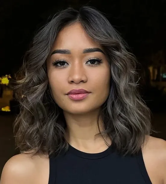 Frizura do ramena s valovitim pramenovima koja uravnotežuje širinu pravokutnog lica.