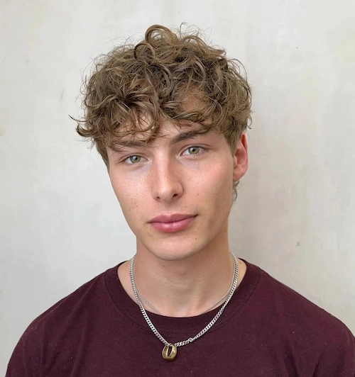 Kratka valovita shag frizura za muškarce s dijamantnim oblikom lica koja uravnotežuje jagodice i omekšava čelo.