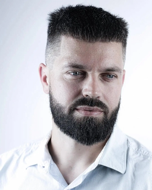 Kratka muška frizura s duljim vrhom koja održava ravnotežu pravokutnog lica bez dodatne visine.