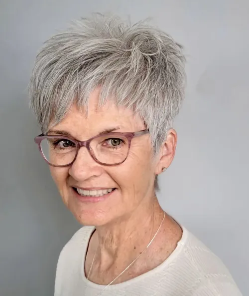 Mladenački sivi undercut pixie s laganim volumenom i urednim oblikom, idealan za žene nakon 70. godine.