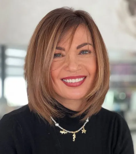 Moderna Rachel frizura srednje dužine s nježnim slojevanjem i pernati vrhovima, idealna za žene nakon 60. godine.