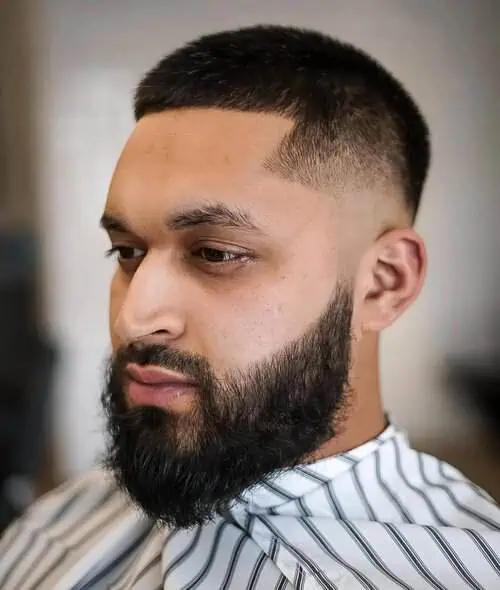 High fade frizura za muškarce s visokim čelom, dopunjena uređenom bradom za više definicije.