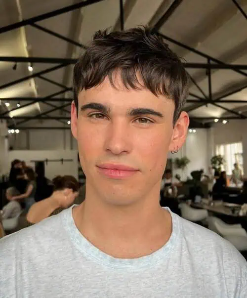 Slojasta muška frizura s frufrujem koja prekriva dio čela i stvara uravnotežen, moderan izgled.