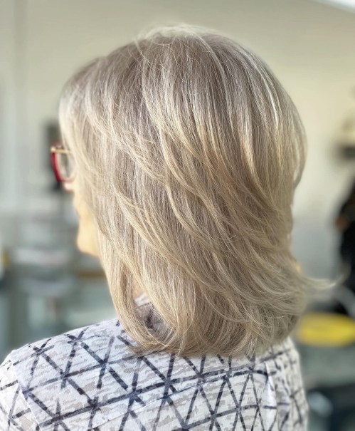 Pernata midi frizura sa slojevima koja dodaje punoću sijedoj kosi i pruža lagan, prozračan stil.