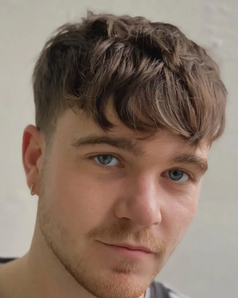 Razored fade frizura koja smanjuje širinu čela i naglašava oči kod srcolikog lica.