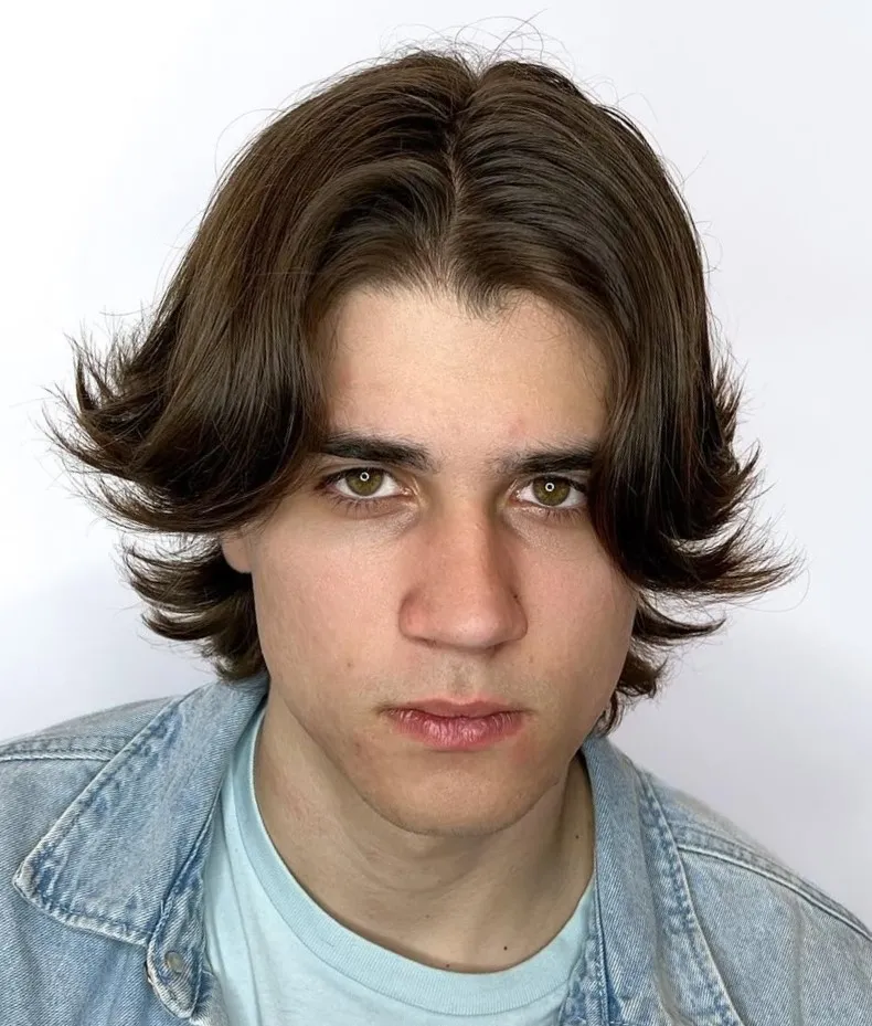 Muška frizura srednje duljine koja stvara prirodan, uravnotežen okvir za ovalno lice.