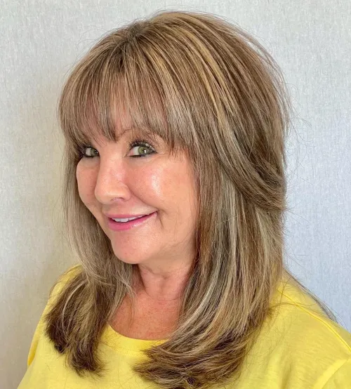 Srednje duga frizura sa šiškama i slojevima za mekši i puniji izgled kose.