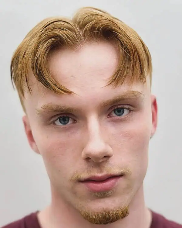 Muška frizura sa srednjim razdjeljkom i blagim valovima koja omekšava široko čelo i uravnotežuje srcoliko lice.