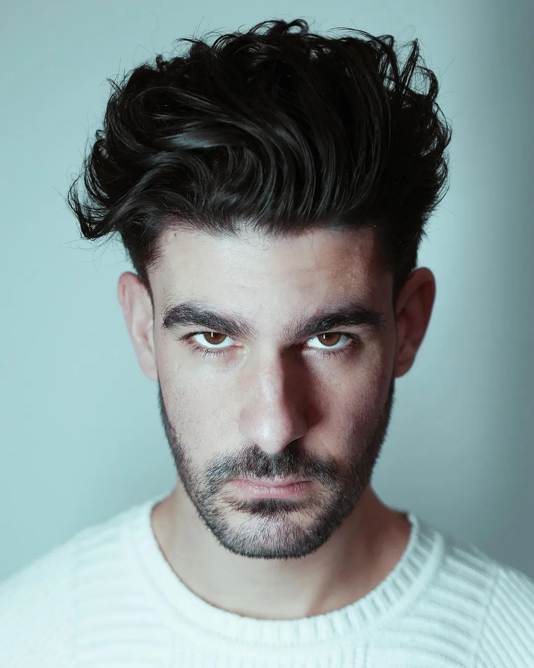 Taper fade frizura s duljim vrhom koja izdužuje kvadratno lice i omekšava snažne linije čeljusti.