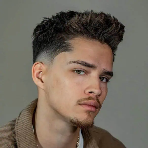 Temple fade muška frizura s duljim vrhom koja uravnotežuje srcoliko lice i vizualno smanjuje širinu čela.