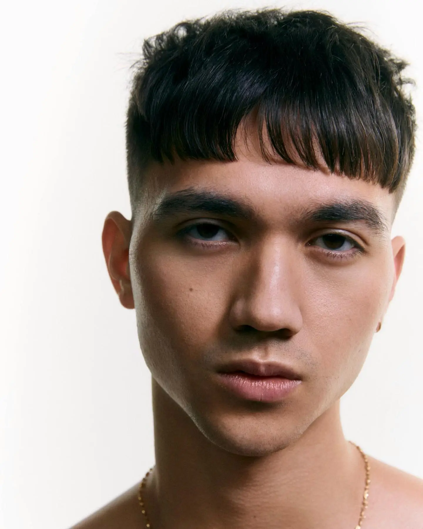 Temple fade frizura s ravnim šiškama koja uravnotežuje ši­re jagodice i uže čelo kod dijamantnog oblika lica.