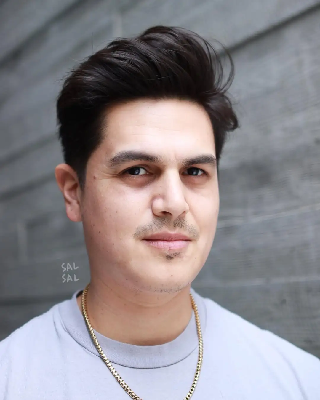 Textured quiff muška frizura koja održava ravnotežu ovalnog lica uz postepeno kraće stranice i dodatni volumen na vrhu.