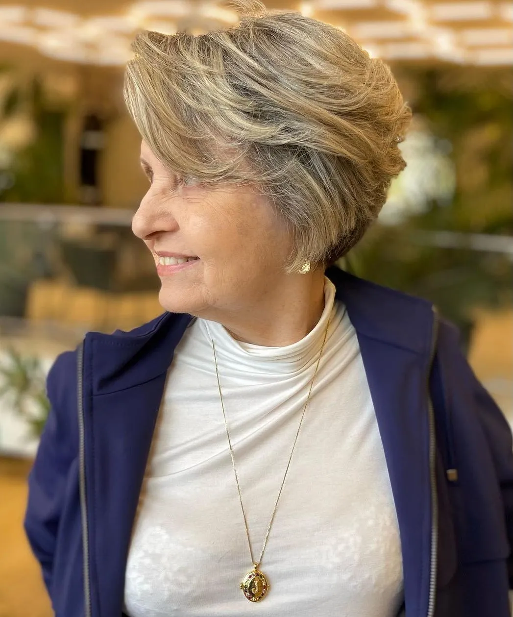 Voluminozan bočno počešljan pixie bob koji podiže kosu na tjemenu i pruža lagan, elegantan izgled za žene nakon 50.