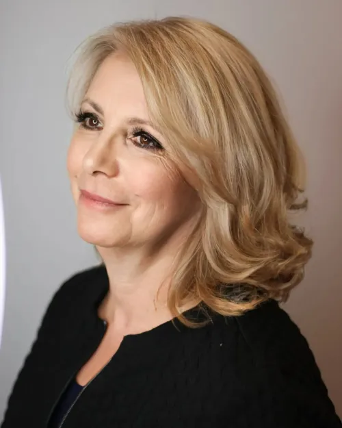 Zlatno svijetla frizura srednje dužine s uvrnutim vrhovima za sofisticiran i osvježavajući izgled.